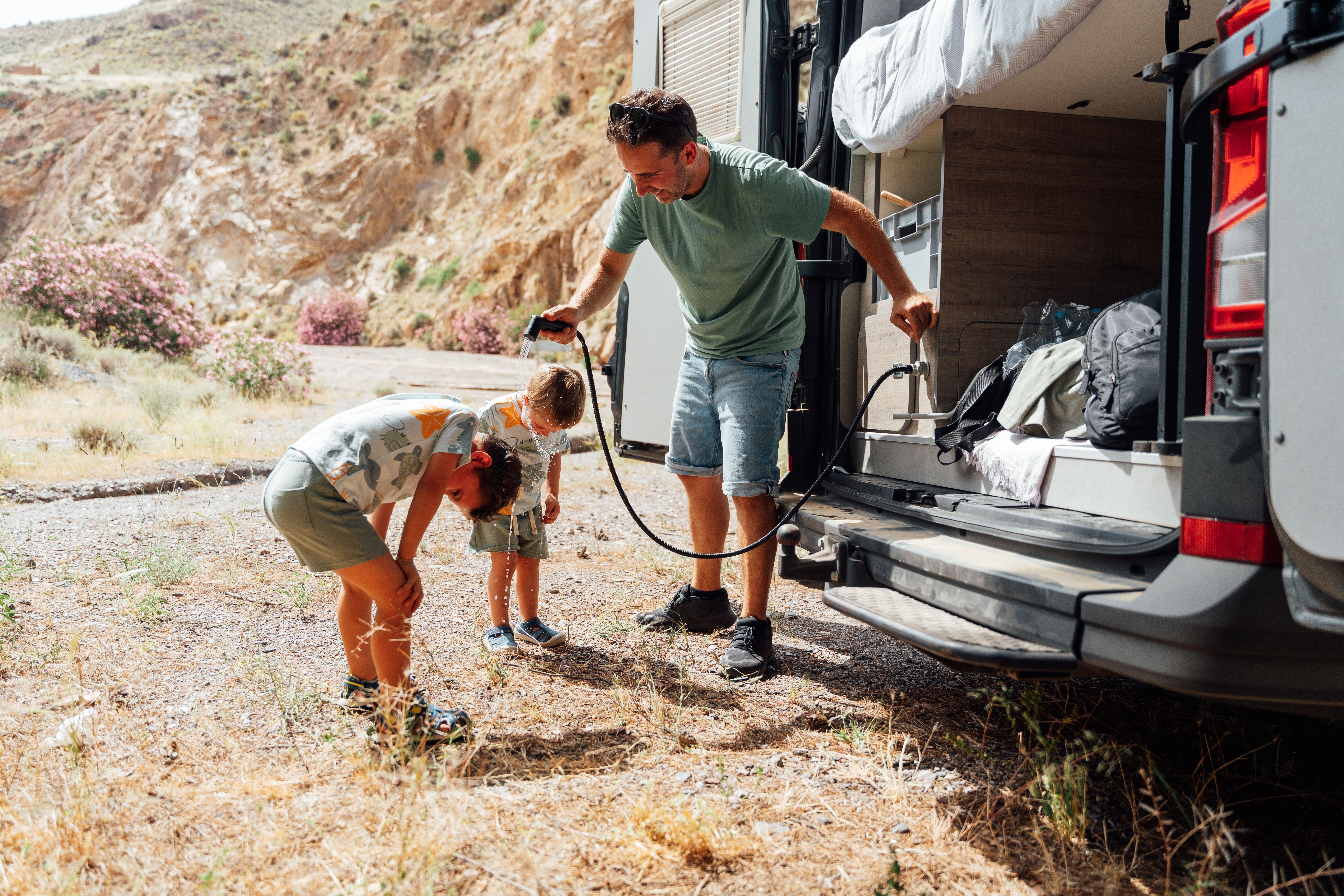 father-and-children-cooling-down-by-camper-van and rv plumbing